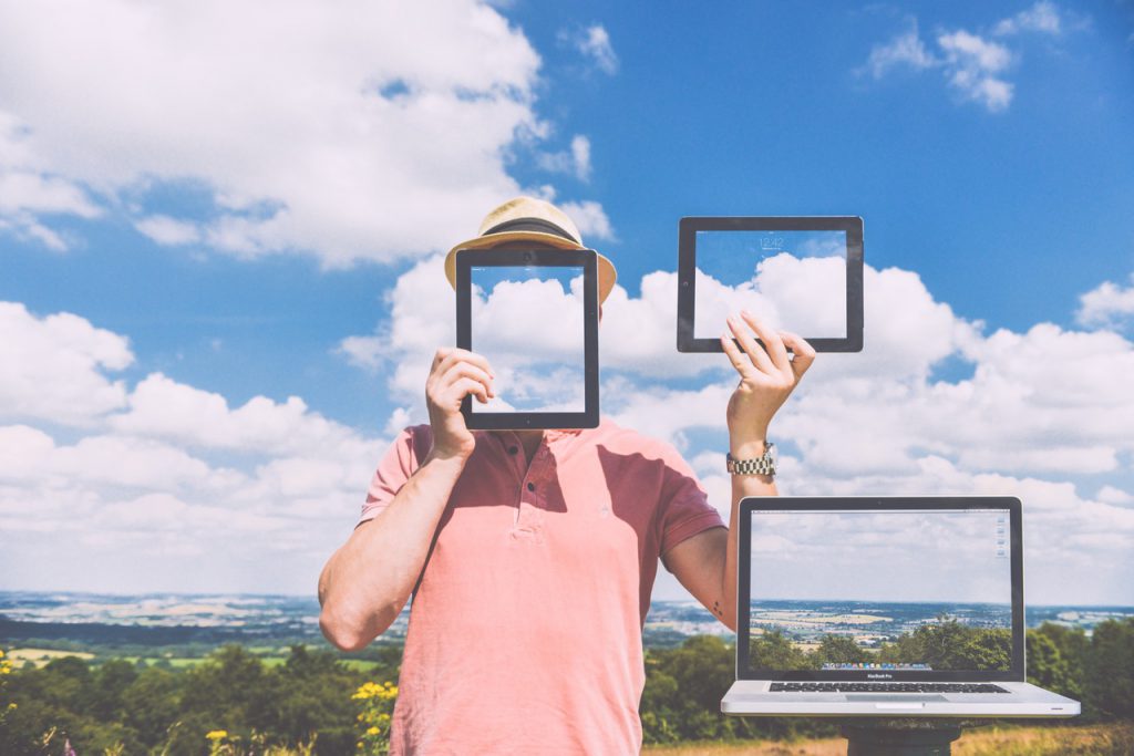 Man holding up tablet screens in front of cloudy sky