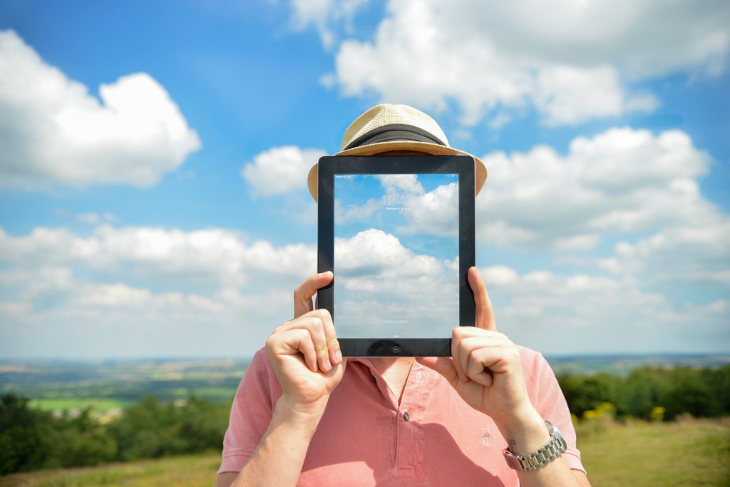 Man holding an Ipad with background of clouds