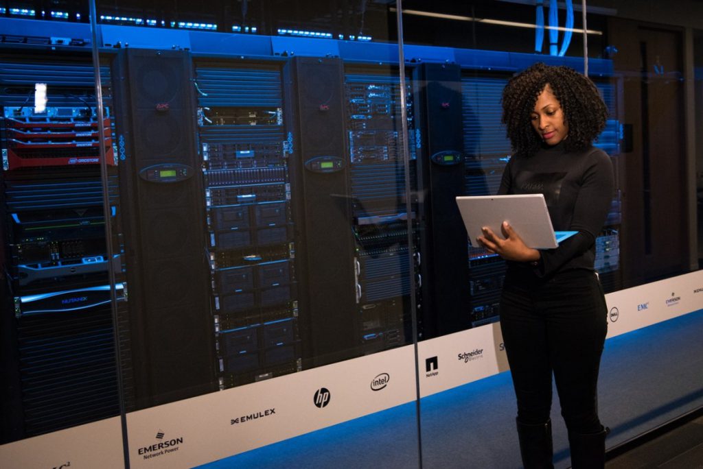 Woman standing with laptop near servers